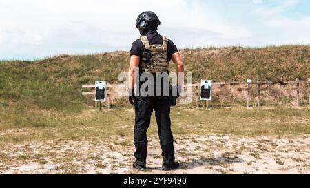 Spezialkräfte in taktischer Ausrüstung üben Feuerwaffentraining auf einem Schießstand unter bewölktem Himmel Stockfoto