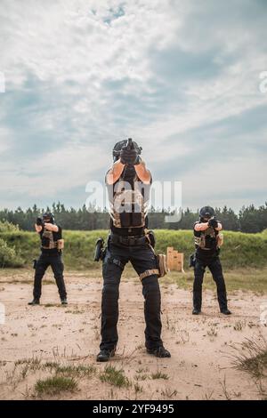 Spezialkräfte in taktischer Ausrüstung üben Feuerwaffentraining auf einem Schießstand unter bewölktem Himmel Stockfoto