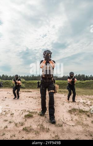 Spezialkräfte in taktischer Ausrüstung üben Feuerwaffentraining auf einem Schießstand unter bewölktem Himmel Stockfoto