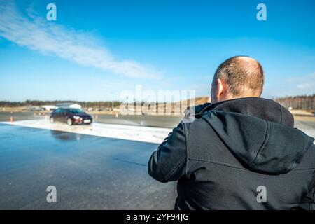 Dynamischer Autobremstest auf nasser Fahrbahn mit Wasserspritzern und orangen Kegeln, Bewertung der Fahrzeugsicherheit in kontrollierter Skidpan-Umgebung Stockfoto