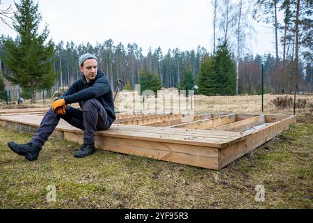 Mann baut eine Holzterrasse oder Terrasse in einer ländlichen Umgebung im Freien, demonstriert heimwerkerfähigkeiten und heimwerkerarbeit Stockfoto