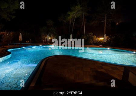 Entspannen Sie sich in einem luxuriösen Touristenresort mit einem wunderschön beleuchteten Swimmingpool, der nachts ein ruhiges Ambiente unter dem Sternenhimmel schafft Stockfoto