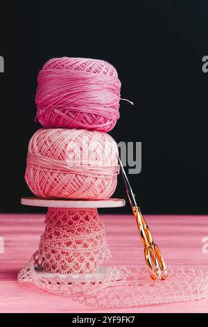 Nahaufnahme von Garn- und Bändchenbällchen neben einer schönen Eisenschere, perfekt zum Stricken, Häkeln und Inspiration für DIY-Projekte. Stockfoto