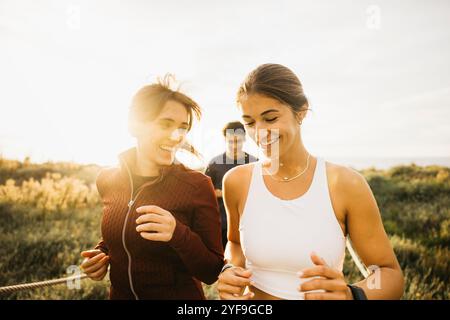 Zwei Freunde joggen an einem sonnigen Tag zusammen und genießen Fitness und Lachen in einem Naturpark. Die Szene fängt Gesundheit, Gesellschaft, an ein Stockfoto
