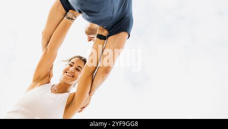 Ein fröhliches Paar, das sich an verspielten Aktivitäten im Freien erfreute. Das Bild fängt Freude, Verbundenheit und ein Gefühl der Freiheit gegen eine helle Ske ein Stockfoto