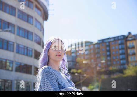 Durchdachte lila Haarfrau mit Brille auf der Straße Stockfoto