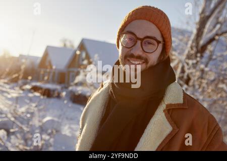 Porträt eines lächelnden Mannes mit Brille und warmer Kleidung im Hinterhof im Winter Stockfoto