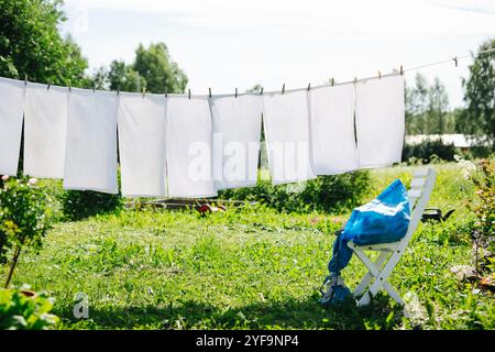 Weiße Kleidung, die an sonnigen Tagen über dem grasbewachsenen Feld trocknet Stockfoto