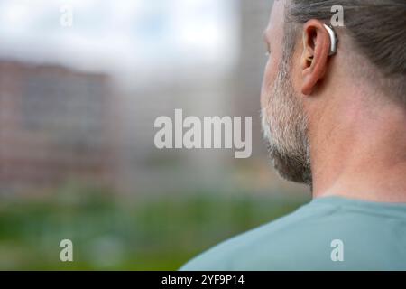 Rückansicht eines Mannes mit grauem Bart, der Hörgeräte trägt Stockfoto