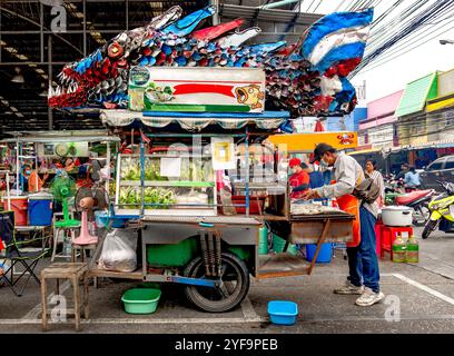 Chonburi, Thailand, 18. Oktober 2023: Ein Verkäufer, der nur Holzkohle gegrillten Fisch mit einem großen Metallfisch auf dem Dach seines Trucks verkauft. Stockfoto