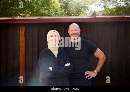 Porträt eines glücklichen Paares, das vor einer Holzwand steht Stockfoto