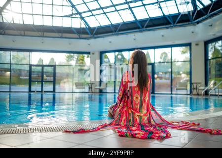 Eine hübsche junge Frau, die sich am Pool im Spa erholt Stockfoto