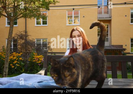 Porträt einer jungen Frau mit schwarzer Katze, die auf dem Hof sitzt Stockfoto