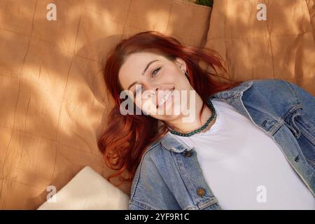 Porträt einer schönen jungen Frau, die auf einer Matte im Park ruht Stockfoto