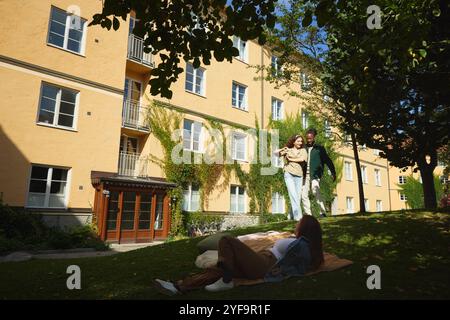 Junge Frau ruht sich aus, während Freunde im Park tanzen Stockfoto