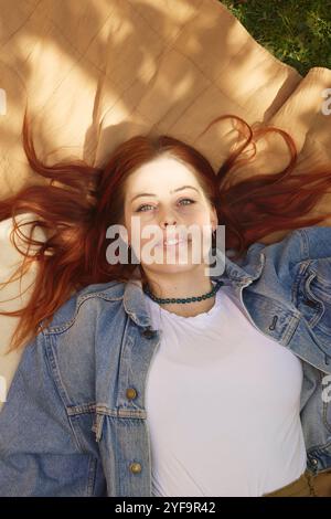 Hochwinkelporträt einer jungen Frau, die auf Picknickdecke liegt Stockfoto
