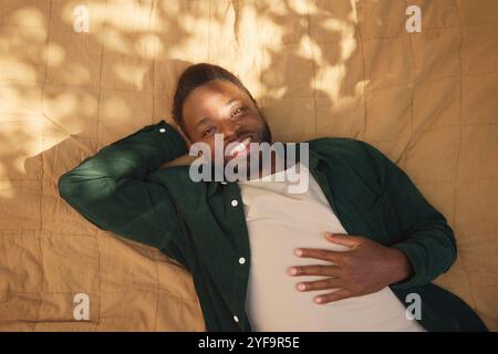 Porträt eines lächelnden jungen Mannes, der auf einer Decke liegt Stockfoto