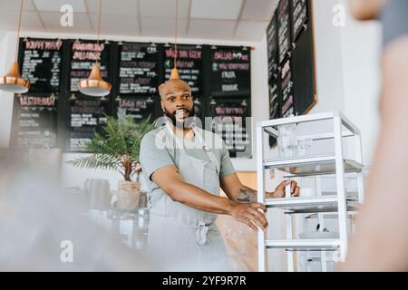 Niedriger Blickwinkel auf den überraschten Kellner, der den Servierwagen im Café hält Stockfoto