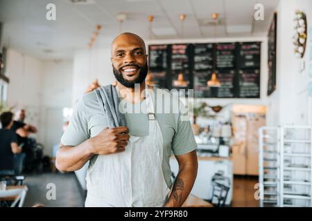 Porträt eines lächelnden Kellners, der im Café steht Stockfoto