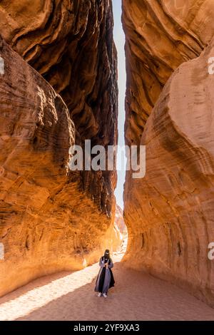 AL ULA, SAUDI-ARABIEN - 9. NOVEMBER 2021: Ortskundiger Reiseleiter in der engen Passage durch den Berg Jabal Ithlib, den Siq, bei Hegra (Mada'in Salih) in der Nähe Von A Stockfoto