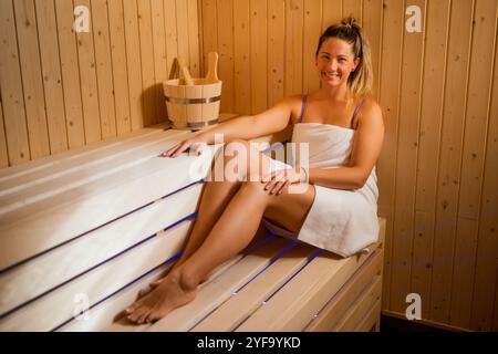 Erwachsene Frau entspannt sich in der Sauna. Frau sitzt in der Sauna und genießt eine gesunde Behandlung. Stockfoto