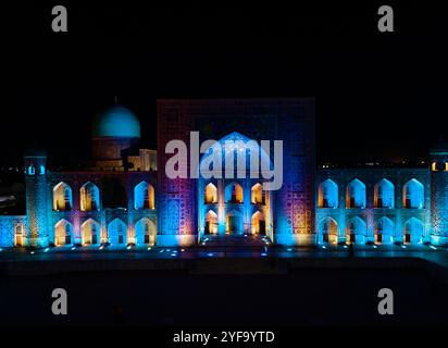 Samarkand, Usbekistan, aus der Vogelperspektive auf den farbenfrohen Registan-Platz bei Nacht. Übersetzung zur Moschee: "Ulugh Beg Madrasah und die Tilya-Kori Madrasah". Stockfoto