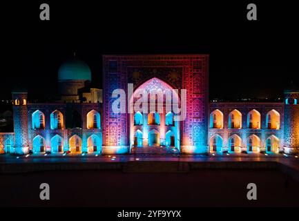 Samarkand, Usbekistan, aus der Vogelperspektive auf den farbenfrohen Registan-Platz bei Nacht. Übersetzung zur Moschee: "Ulugh Beg Madrasah und die Tilya-Kori Madrasah". Stockfoto