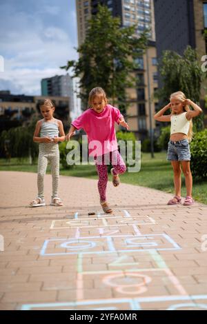 Mädchen, die im Sommer im Hof Hopscotch spielen Stockfoto