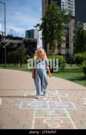 Mädchen, die im Sommer im Hof Hopscotch spielen Stockfoto