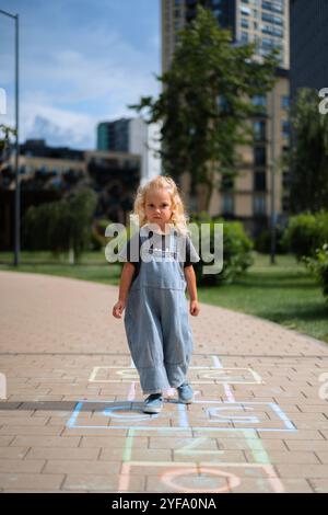 Mädchen, die im Sommer im Hof Hopscotch spielen Stockfoto