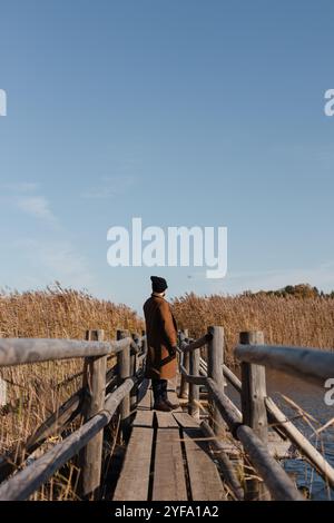 Ein Mensch und eine Libelle auf einer Brücke gegen Schilfbüsche und blauen Himmel Stockfoto