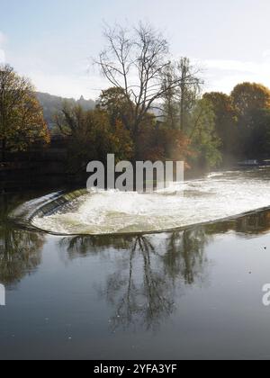 Pulteney-Wehr, in Wolke nach starkem Regen mit Herbstbäumen dahinter, spiegelt sich im Wasser des Flusses Avon. Bad, Somerset. Touristenattraktionen. Stockfoto