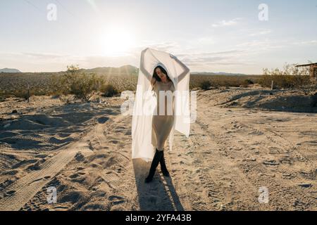 Frau in der Wüste mit transparentem Stoff unter der warmen Sonne Stockfoto