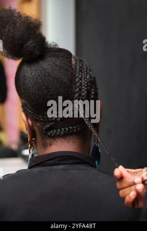 Der Friseur flechtet im Salon Zöpfe in das Afro-Haar des Kunden Stockfoto