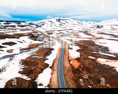 Atemberaubende Aussicht auf Islands dramatische Landschaft mit schneebedeckten Bergen und einem Fluss, der sich durch ein zerklüftetes Tal schlängelt. Stockfoto