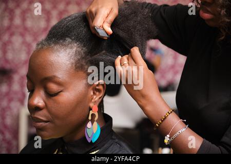 Friseur flechtet die Afro-Haare des Kunden im Salon Stockfoto