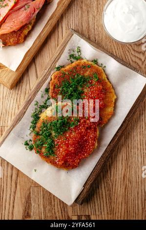 Kartoffelpfannkuchen mit rotem Kaviar auf einem Holzteller Stockfoto