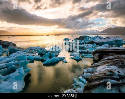 Atemberaubende Aussicht auf die Jokulsarlon Glacier Lagoon bei Sonnenuntergang mit atemberaubenden Eisbergen, die in den ruhigen Gewässern von Islands beliebtesten schwimmen Stockfoto