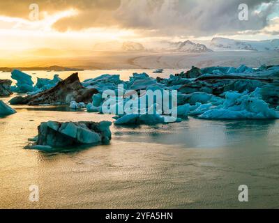 Blick aus der Vogelperspektive auf die Jokulsarlon Gletscherlagune bei Sonnenuntergang mit atemberaubenden blauen Eisbergen im ruhigen Wasser von Islands berühmtem Reiseziel. Stockfoto