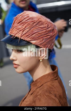 MAILAND, ITALIEN - 19. SEPTEMBER 2024: Frau mit Hut mit rosa Federn und Wildlederjacke vor der Prada Fashion Show, Mailand Street Style Stockfoto