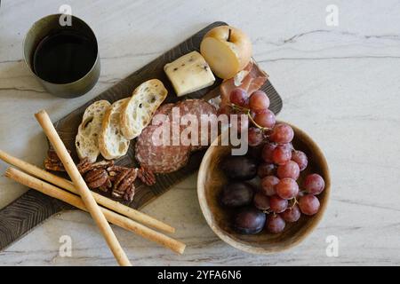 Wurstplatte mit Käse, Trauben, Birne, Nüssen und Wein auf einem Tisch Stockfoto