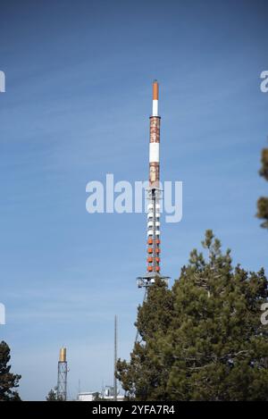 Kommunikationsturm auf einem Gebäude mit 4G 5G Antenne und Satellitenschüssel gegen blauen Himmel. Mobile Kommunikation Stockfoto