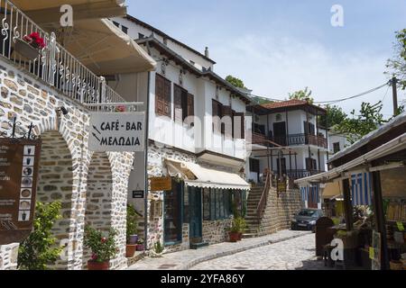 Ein bezauberndes Straßencafé in einem traditionellen Dorf mit Steinhäusern und Holzbalkonen, beleuchtet von Sonnenschein, Makrinitsa, Balkon von Pilion, Municipalit Stockfoto