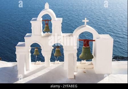 Traditionelle weiße blaue christliche Kirche Kuppel Glockenturm und Metallglocken. Santorini Insel in Griechenland. Griechische Inseln Sommerferien Stockfoto