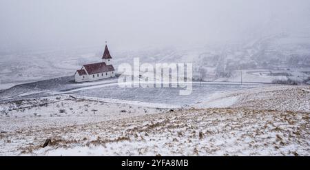 Die malerische Vik i Myrdal Kirche auf dem Gipfel des Hügels bietet malerische Bilder des atlantischen Ozeans und des Dorfes vik in Island Stockfoto