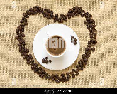 Kaffeebohnen in Form eines Herzsymbols und eine Tasse schwarzen Espresso. Konzept von I love Coffee Stockfoto