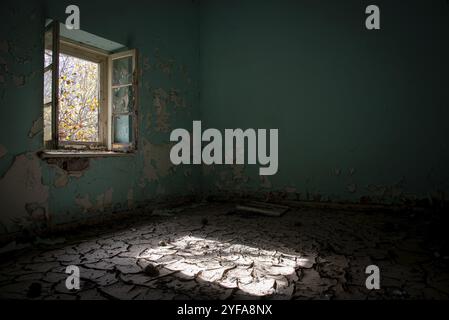 Innenraum einer schmutzigen und leeren abgerissen aufgegeben mit offenem Fenster trocken und rissig Schlamm Stockfoto