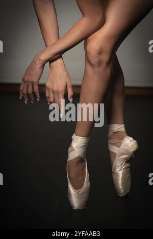 Schöne Beine von jungen Ballerina mit spitzenschuhen tanzen auf einem schwarzen Boden Hintergrund. Ballettübung. Schöne schlanke anmutige Füße des Balletttanzes Stockfoto