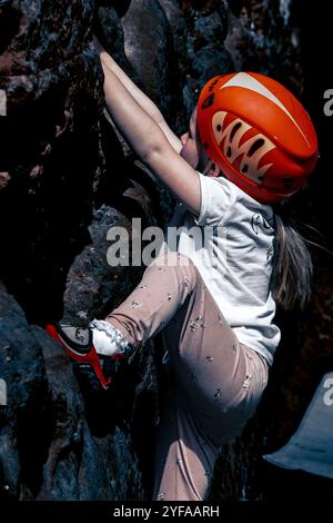 5-jähriges Mädchen klettert und Bouldern mit roten und schwarzen Kletterschuhen. Stockfoto