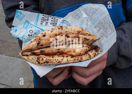 London, Großbritannien. 31. Oktober 2024. Ein Kunde stellt eine Pizza, eine Portafoglio, oder eine gefaltete Brieftasche Pizza, aus einem Pop-up-Stand namens Sud Italia, der auf dem Spitalfields Market holzbefeuerte neapolitanische Pizzen verkauft. Quelle: Mark Kerrison/Alamy Live News Stockfoto